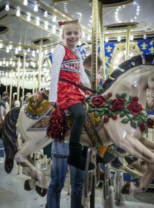 Young girl dressed in costume riding the carousel at night