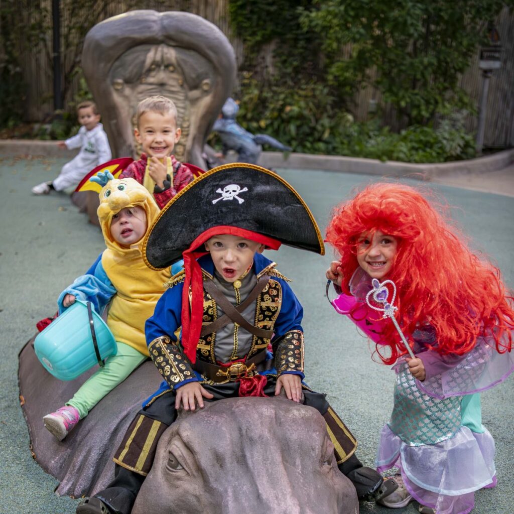 Young children in Halloween costume sitting on hippo statues