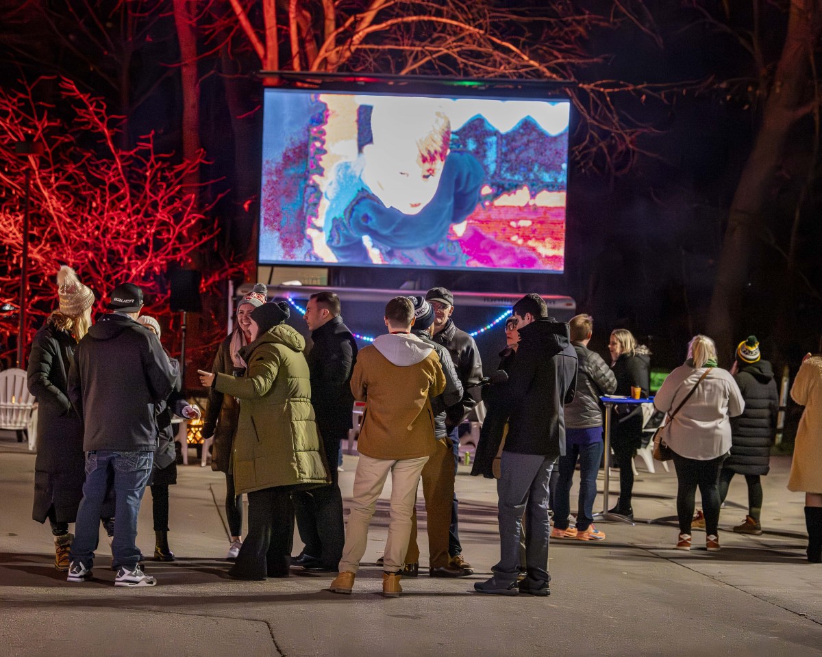 Crowd standing in front on outdoor movie showing