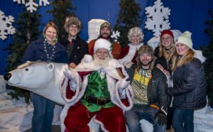 Group of adults posing with Santa and Mrs. Claus