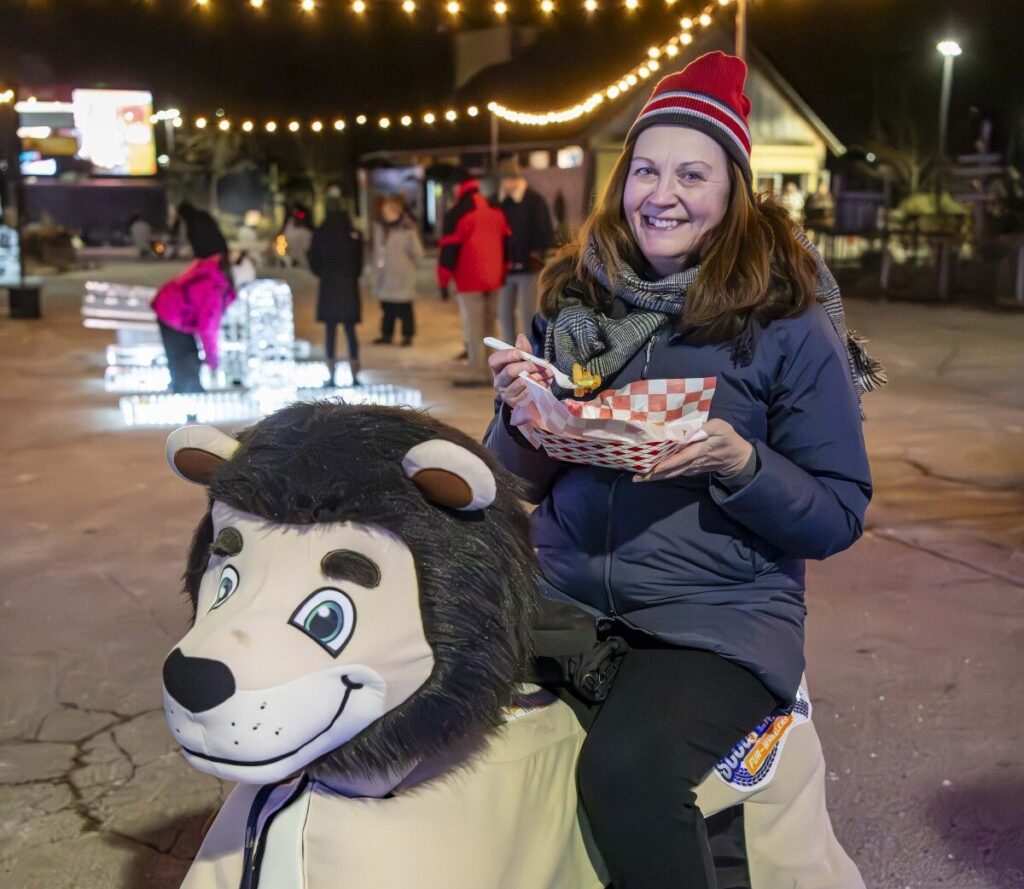 Woman holding food while driving a mobile scooter dressed like a lion