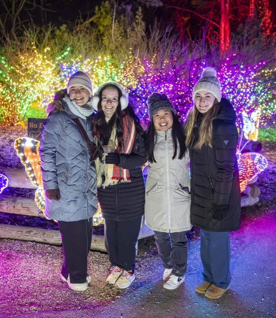 Group of female friends standing outside in front of holiday lights