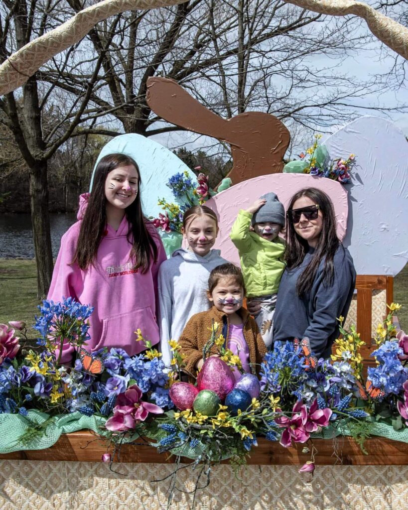 Family poses in front of a springtime background at Egg Day