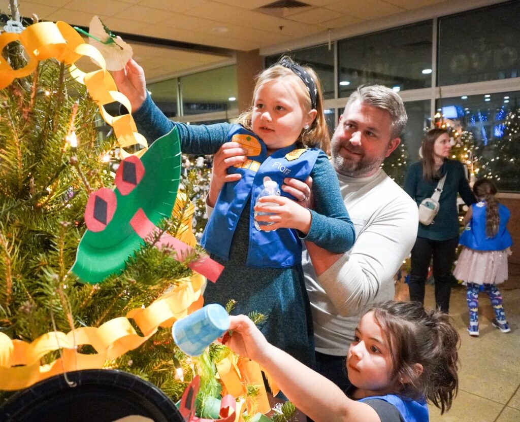 Little girls decorating a Christmas tree with their father