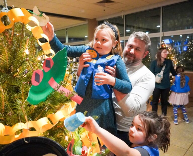 Little girls decorating a Christmas tree with their father