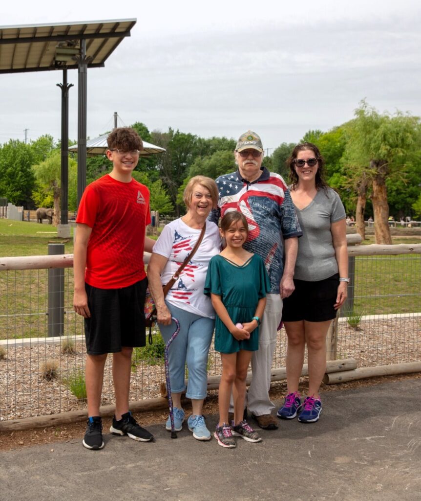Family dressed in patriotic clothing standing in front of outdoor elephant habitat
