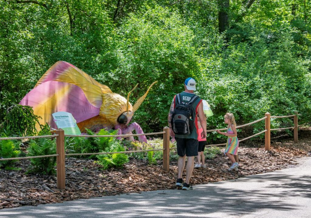 Father and young daughters looking at a giant animatronic pollinator