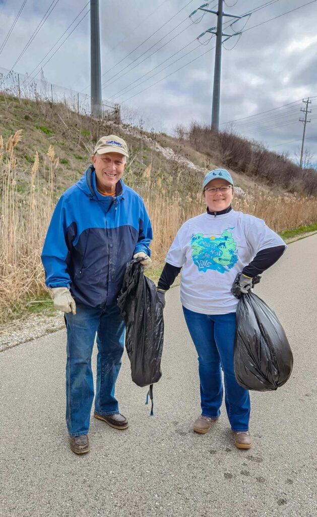 Two people holding bags full of garbage litter
