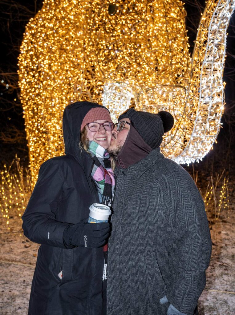 Couple kissing in front of an illuminated elephant sculpture at night