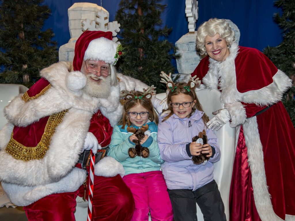 Two children posing with Santa and Mrs. Claus
