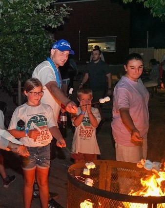 Campers roasting marshmallows around a fire pit